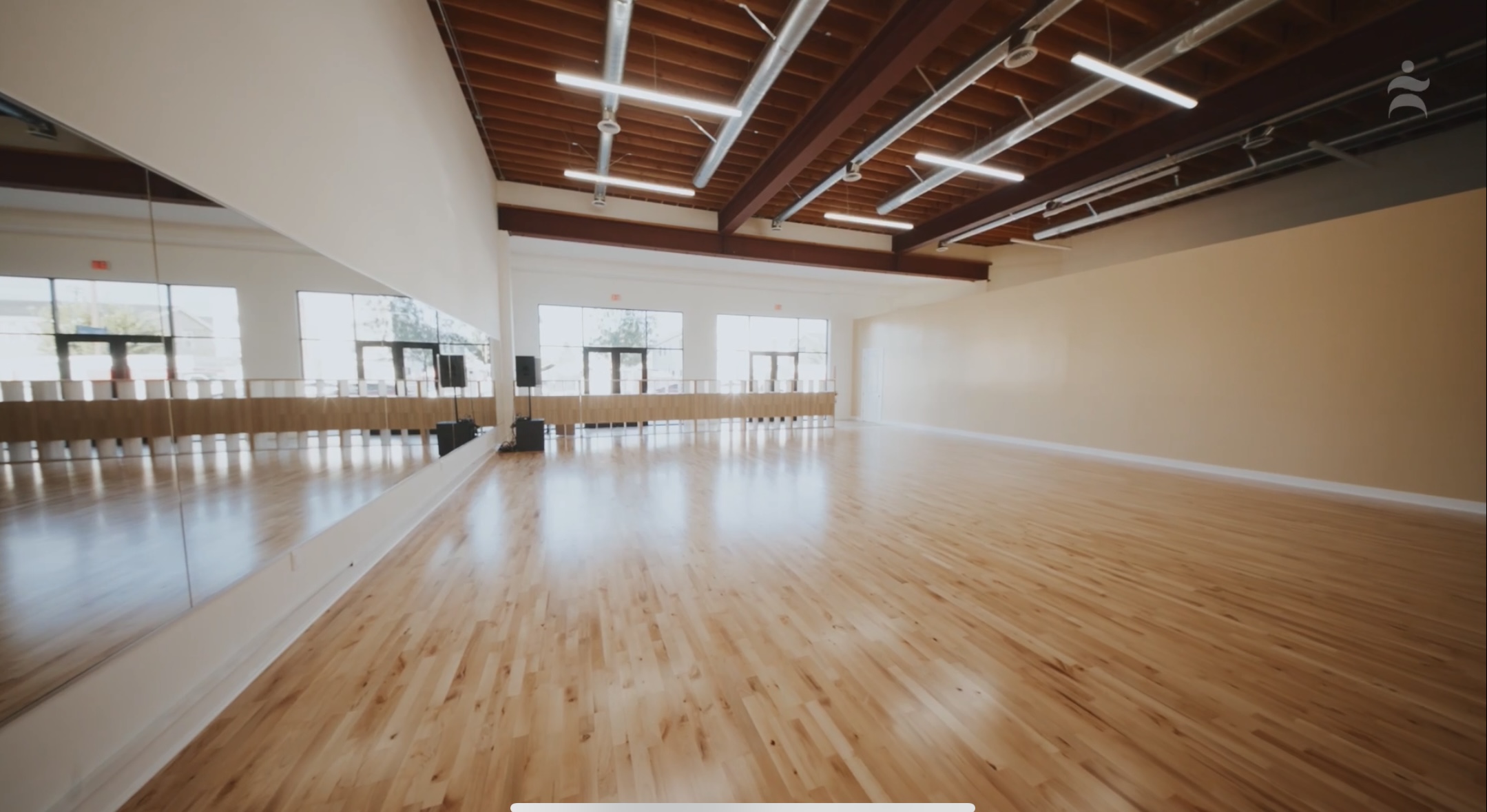Main dance studio with hardwood floor, full-length mirrors and high wood-beam ceiling