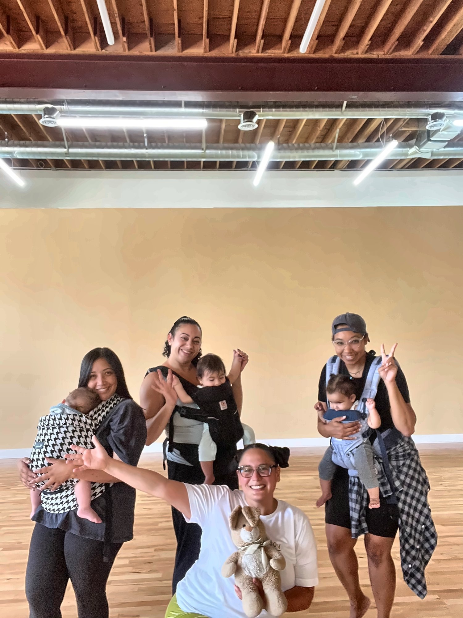 Moms dancing with their babies in carriers at Baby Dance Club